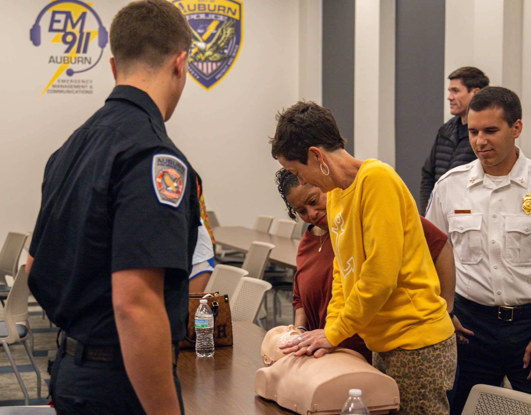 Participant doing CPR on a dummy while instructors look on