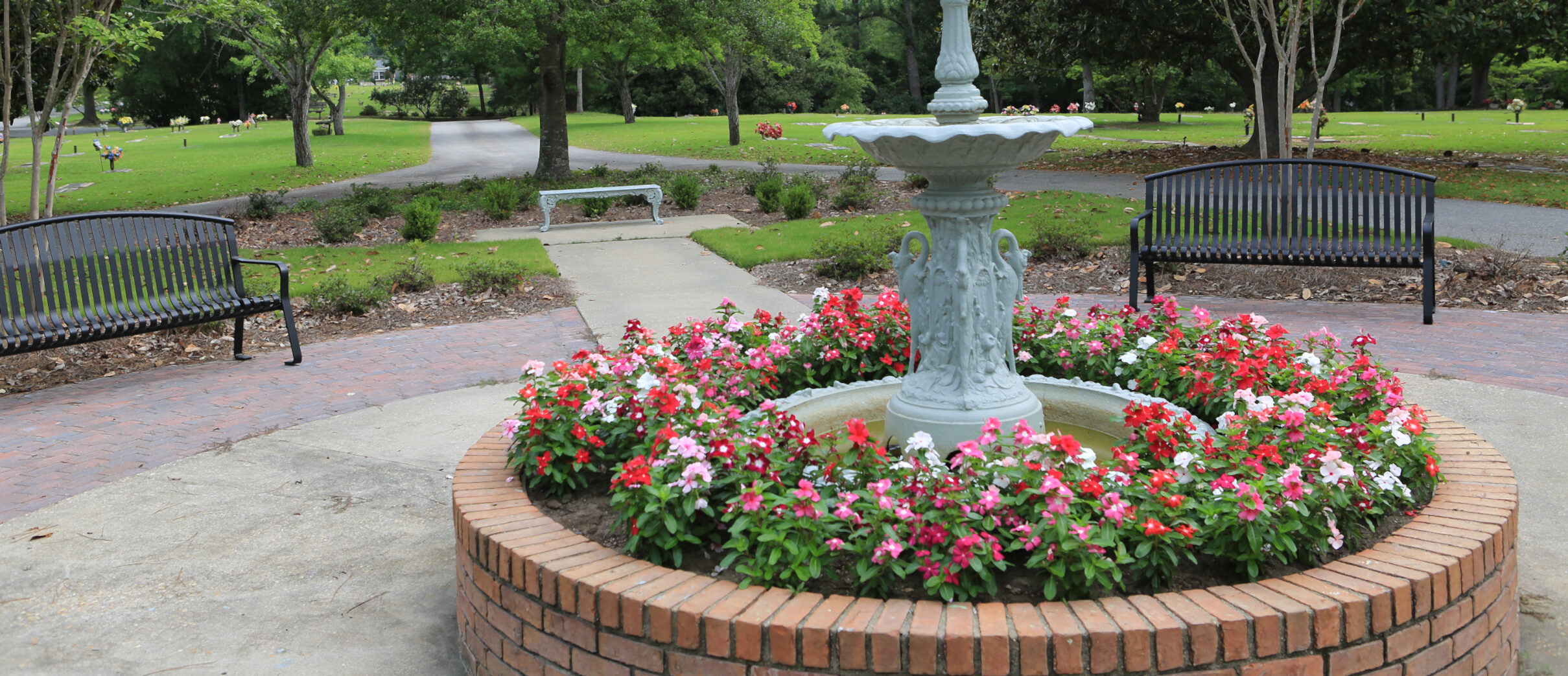 Fountain with floral landscaping with benches placed around.