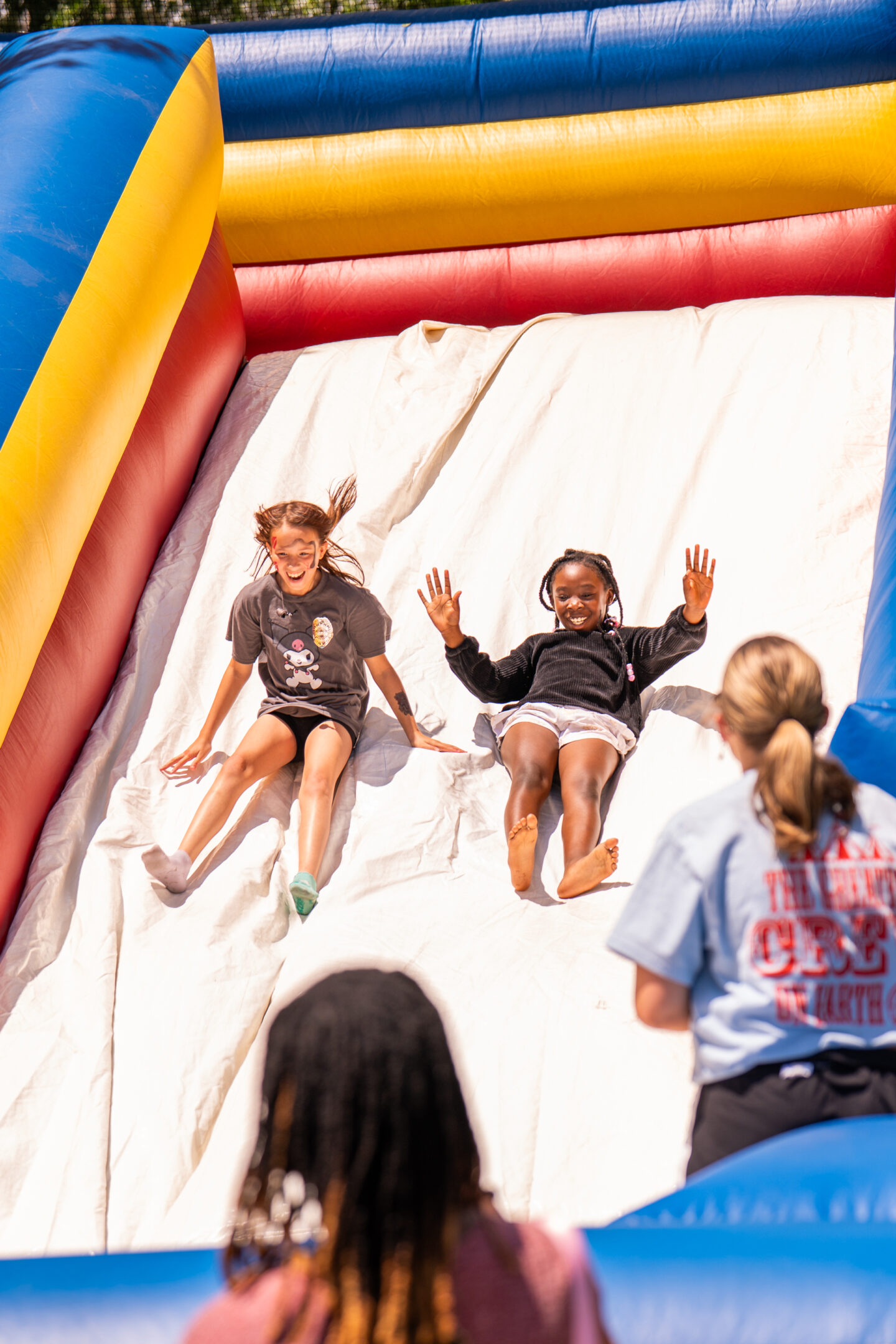 Children sliding down an inflatable slide at an outdoor event.