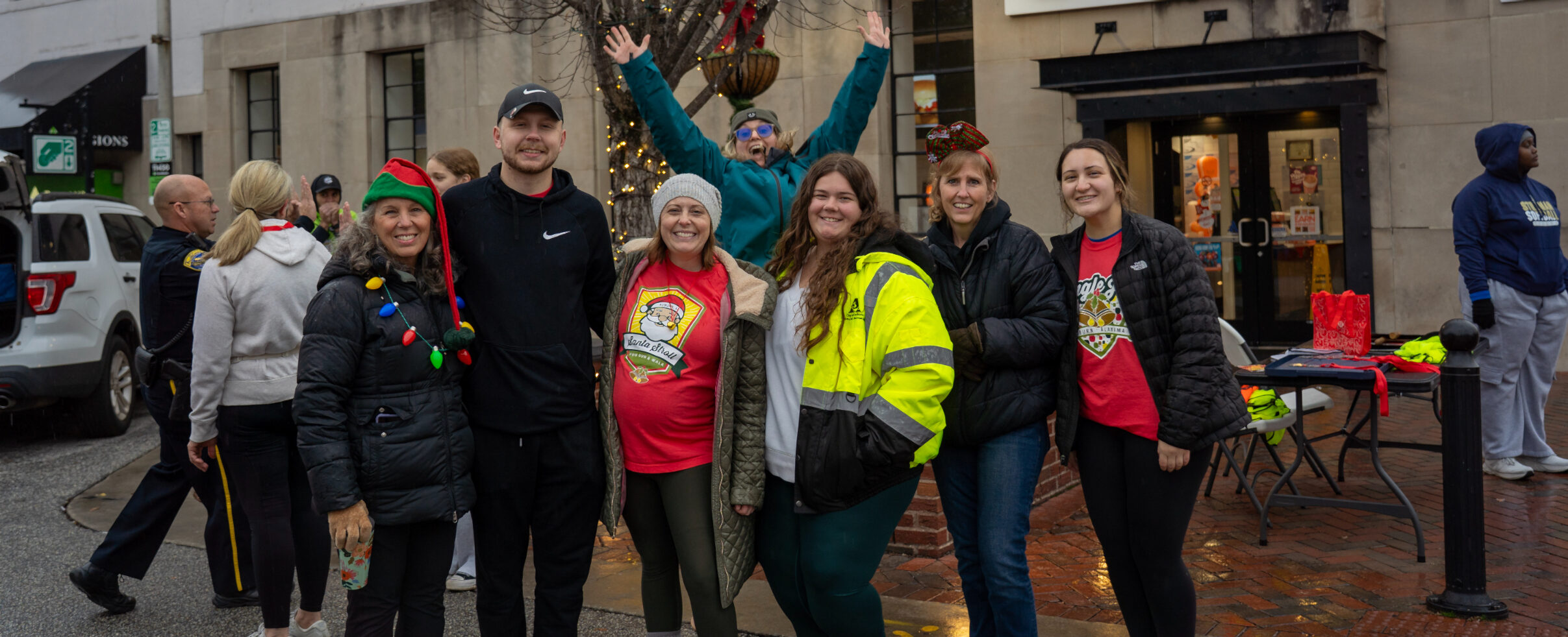 Group of people smiling and posing on a city street wearing festive attire during a cmmunity event.