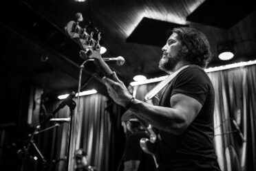 Black and white image of man on stage holding guitar.