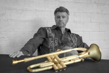 Man sitting at table with trumpet in front of him.