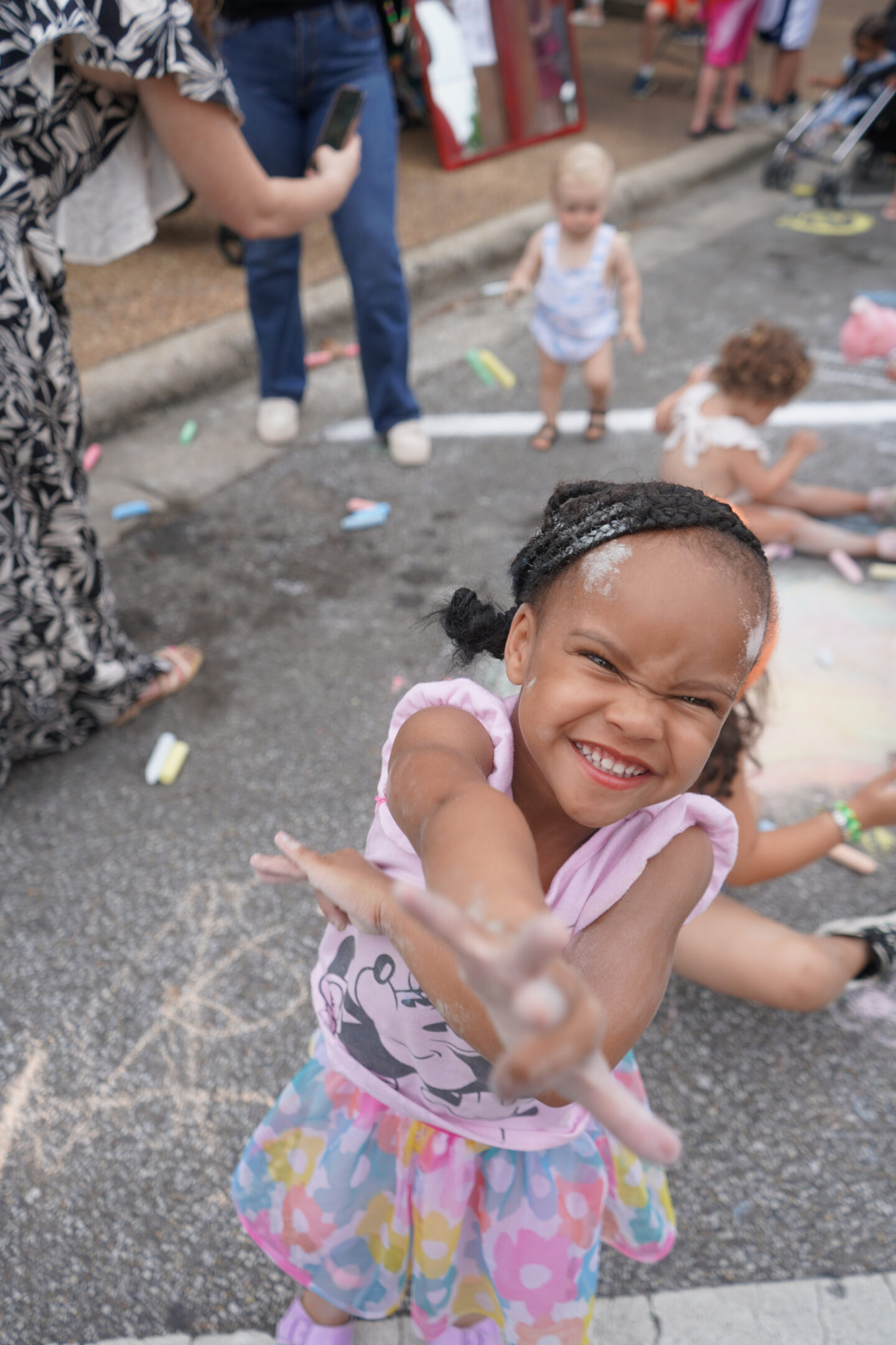 Image show young girl playing with chalk on the sidewalk