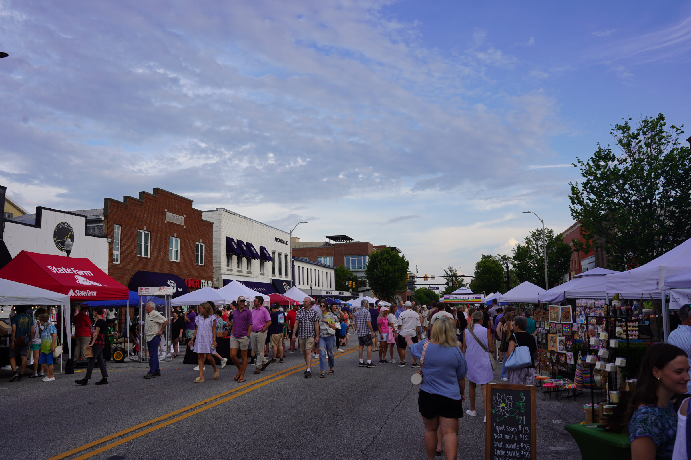 Image shows around 150 people walking down the middle of the street during the SummerNight Arts Festival