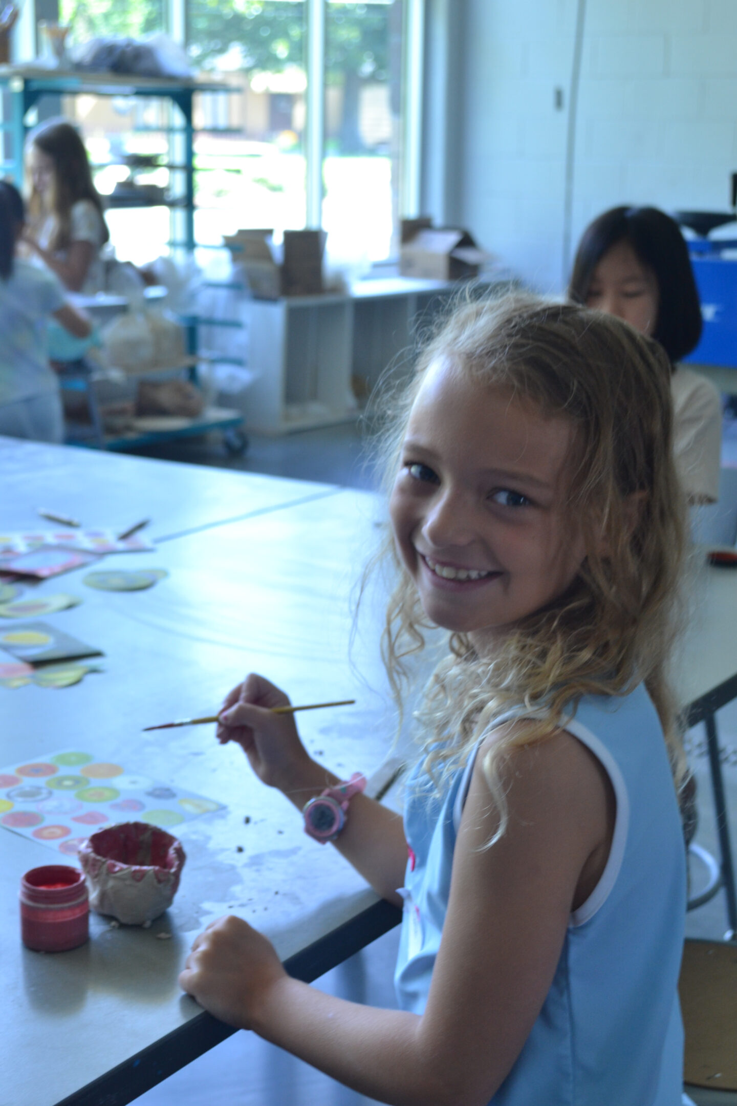 Picture should young art camper painting their piece on a table in the art studio
