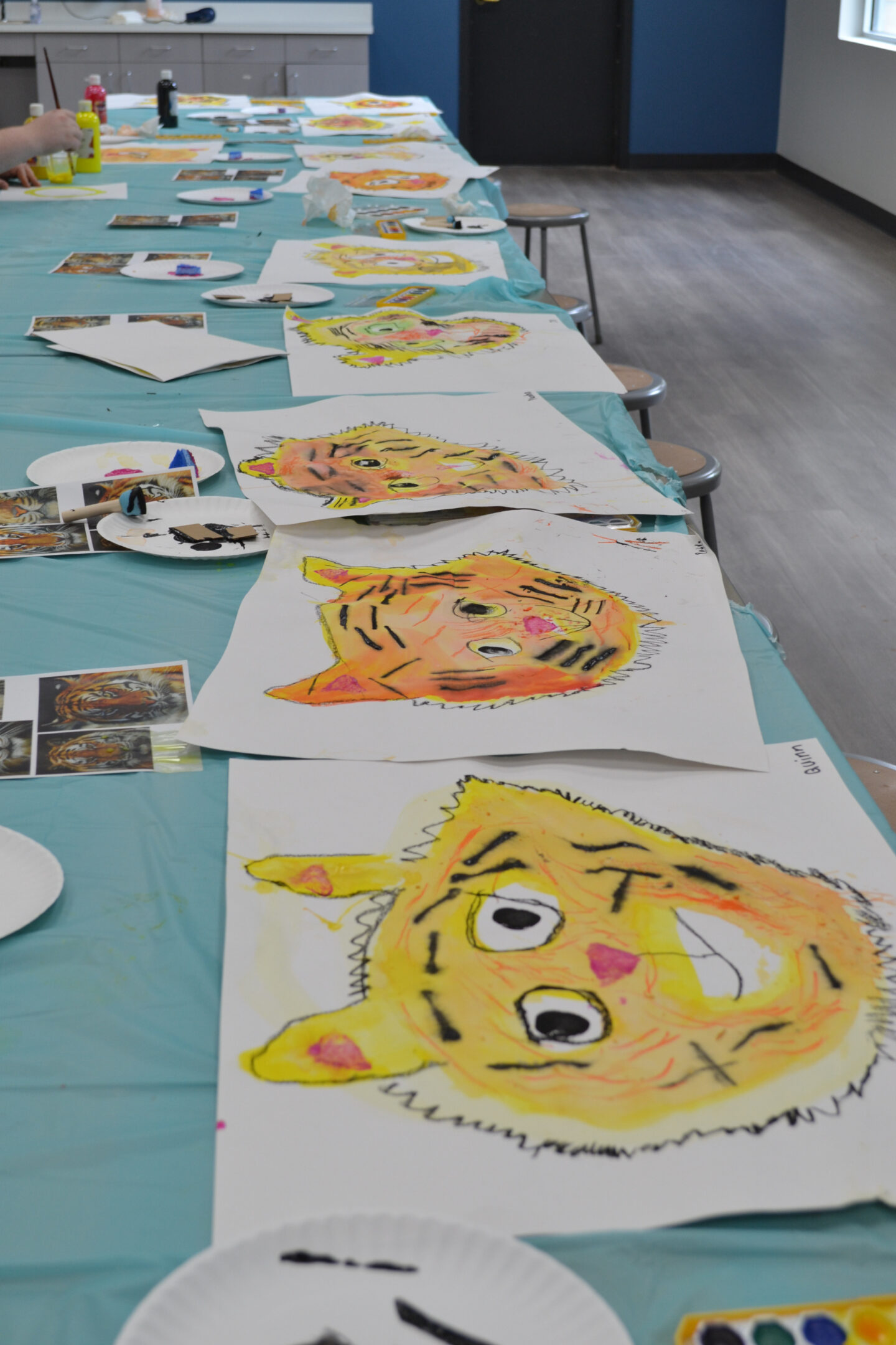 Picture is of a group of art projects showing tigers head drying on a table.