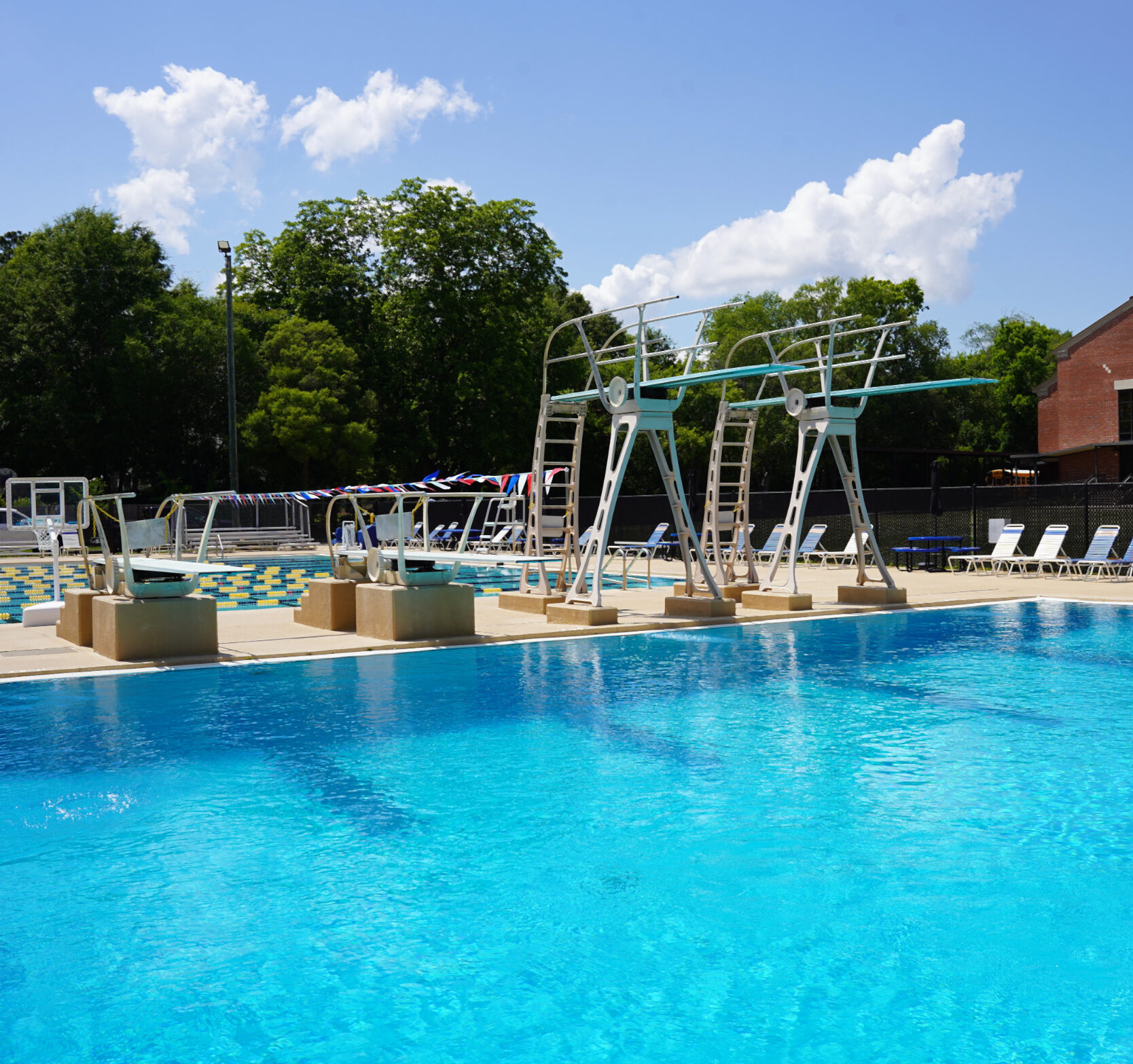 Two low diving board and two high diving boards over a diving well with a lap pool in the background.