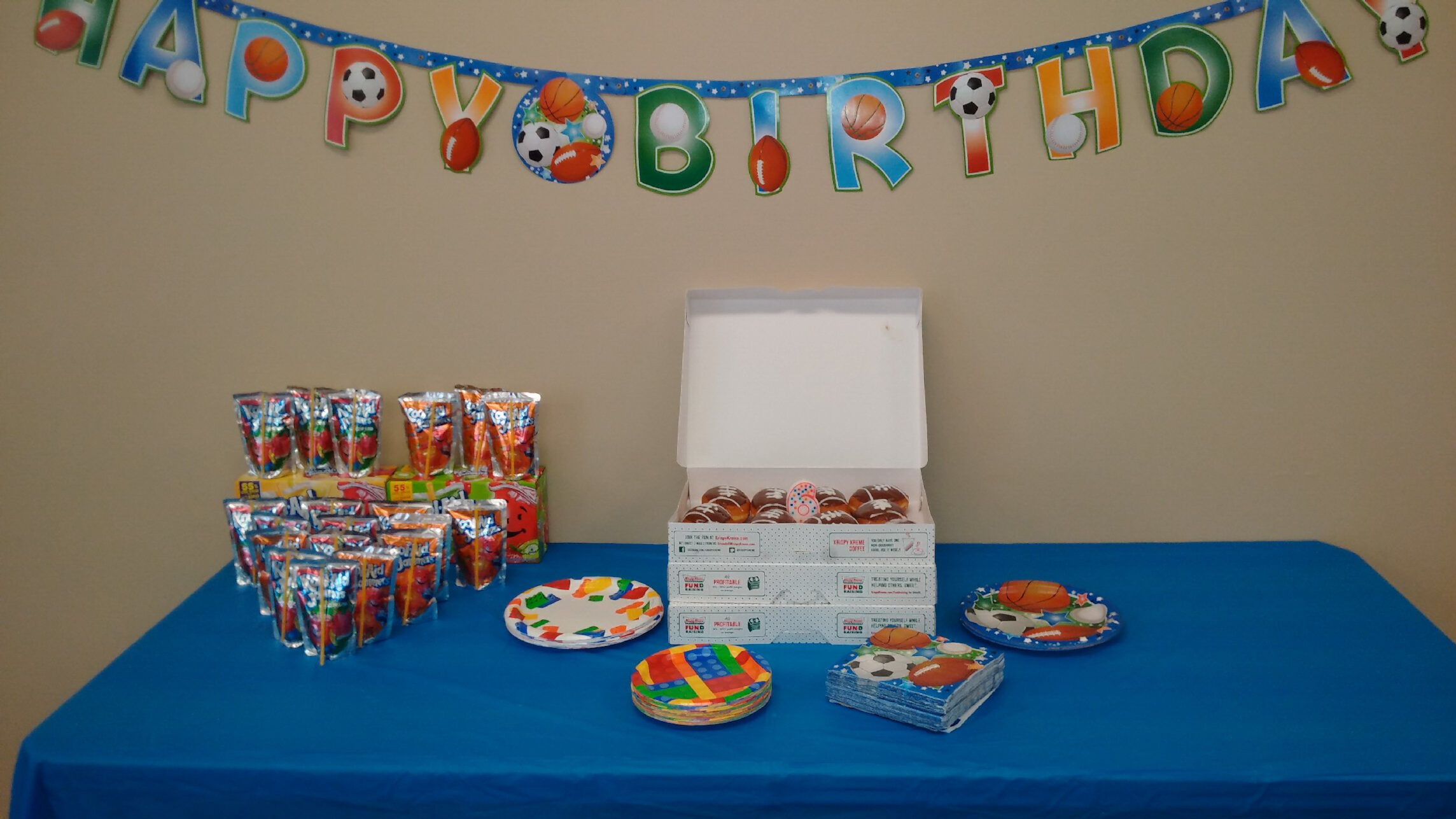 A table with donuts, juice pouches, and borthday themed decorations.
