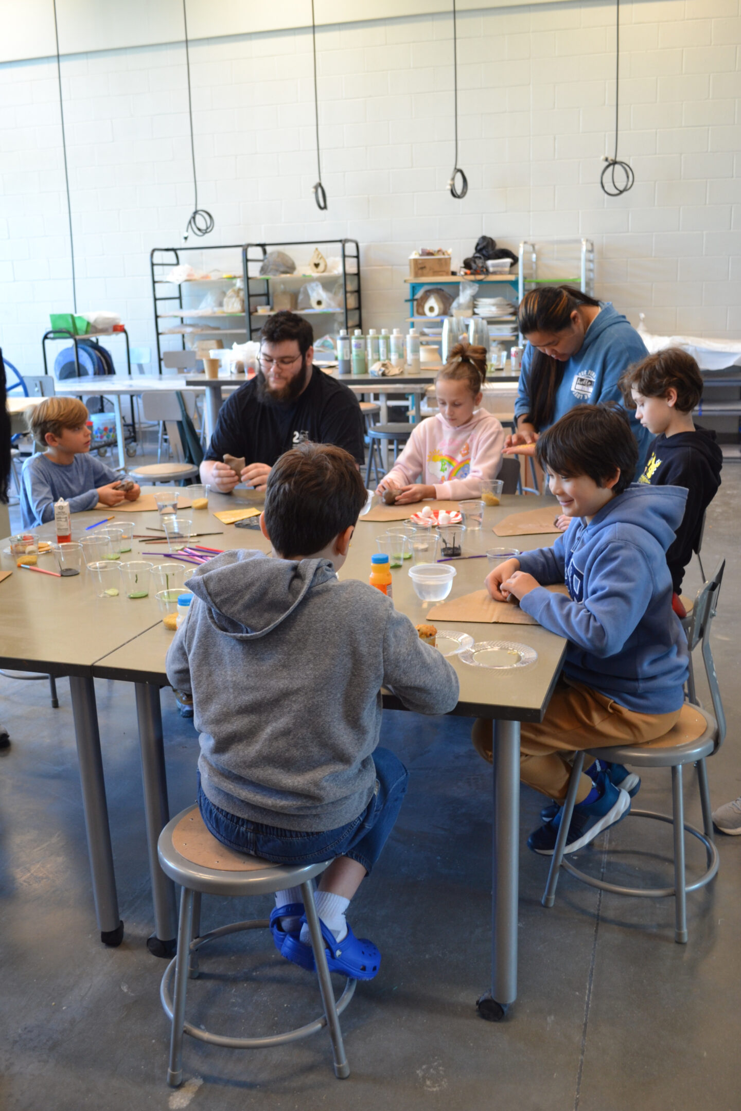 Image shows children and ceramics staff members working on creating a small ceramic turtle sculpture.