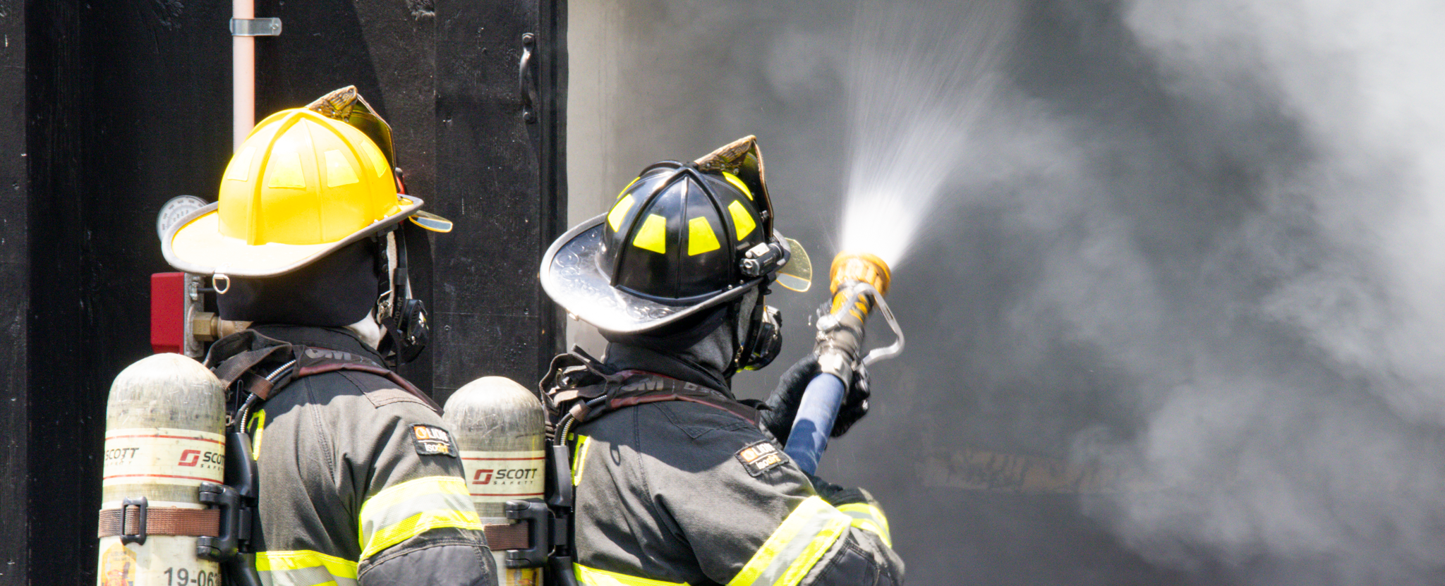 Firefighters spraying fire with hose